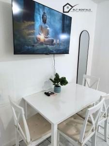 a white table and chairs with a tv on the wall at Modern studio in a prime location 112-1 in Hollywood