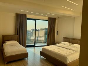 a bedroom with two beds and a large window at Hotel Gramozi in Kaninë