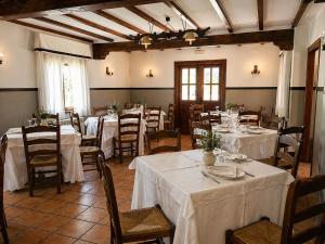 a dining room with tables and chairs with white tablecloths at Posada El Hoyal in Pesaguero-La Parte