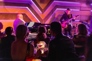 a group of people sitting in a bar watching a man playing guitar at The Sun Rose West Hollywood in Los Angeles +99 photos