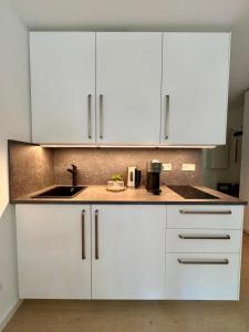 a white kitchen with a sink and white cabinets at Little Dream Konstanz in Konstanz