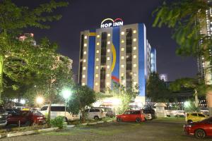 Hop Inn Hotel Ermita Manila في مانيلا: مبنى نزل hogan مع سيارات متوقفة في موقف للسيارات
