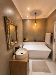 a bathroom with a large tub and a sink at Lenmed Prime Spot in Kimberley