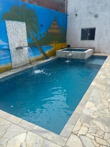 a swimming pool with a fountain in front of a mural at Espaço Recanto dos Sonhos DR in Itaquaquecetuba