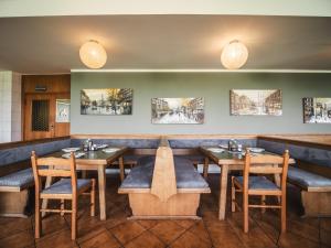 a restaurant with wooden tables and chairs and paintings at Faaker See Inn by Aurora in Faak am See
