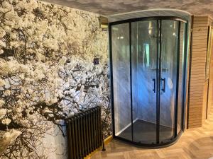 a glass shower in a room with a floral wall at Simons Whody Hideaway in Ulcombe
