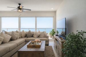 a living room with a couch and a tv at Panoramic Oceanfront Resort Style Condo in Rosarito