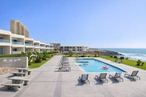 a resort with a swimming pool and chairs and the ocean at Panoramic Oceanfront Resort Style Condo in Rosarito