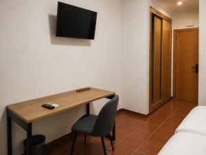 a room with a desk with a chair and a television on the wall at L'Albea Hotel Rural in Vall dʼAlba