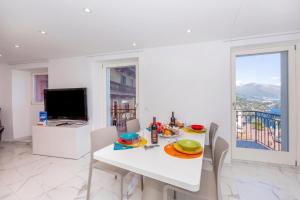 a dining room with a white table and a television at Yellow View Apartment - Ronco S Ascona - Happy Rentals in Ronco sopra Ascona