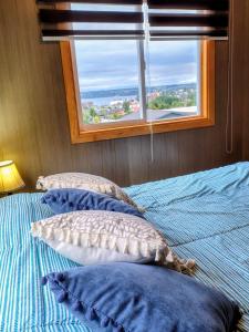 a bedroom with a bed with pillows and a window at Casa kumey in Puerto Varas