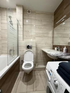 a bathroom with a toilet and a tub and a sink at Apartment Versailles Park 1 in Irpin