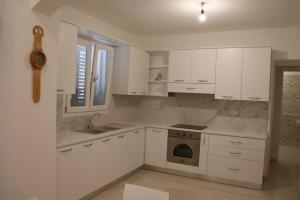 a kitchen with white cabinets and a sink and a stove at Villa Adriano in Salve