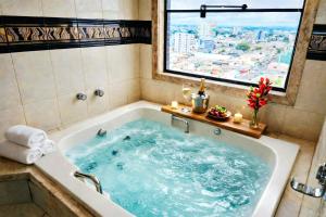 a bath tub filled with blue water in a bathroom at Novo Santoni Hotel Guarapuava in Guarapuava