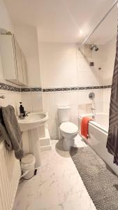 a bathroom with a toilet and a sink and a tub at Spacious 2-Bed Family Flat in Wimbledon Near Tube in London +34 photos