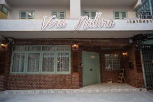 un bâtiment en briques avec un panneau qui lit votre voisin dans l'établissement Vera Nidhra - Self check-in after 7pm, à Bangkok