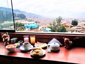 a table with food and drinks and a view of a city at Mirador All Sur Cusco in Cusco
