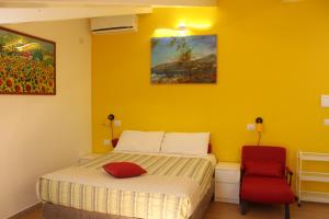 a yellow bedroom with a bed and a red chair at B&B Oasi al Mare in Agropoli
