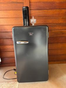 a black refrigerator sitting next to a wooden wall at Chalés Champion Capitolio in Capitólio