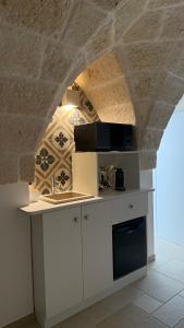 a kitchen with white cabinets and a stone wall at Samy Suite in Fasano