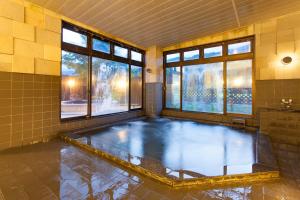 a swimming pool in a room with windows in a bathroom at Schole Hakuba in Hakuba