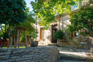 a stone house with a stone wall and trees at Domaine La Cournonsécoise in Cournonsec