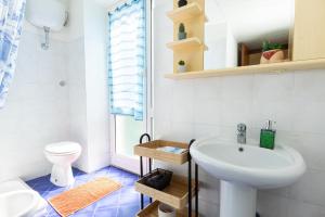a white bathroom with a sink and a toilet at Ria Apartment in Le Grazie +18 photos