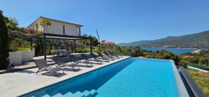 a swimming pool with chairs and a table and a house at Villa Haut Standing Stella Di Mare vue panoramique in Propriano