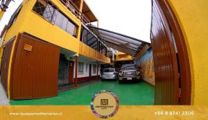 a building with two cars parked in a parking lot at Mediterraneo Hotel in Iquique