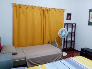 a room with two beds and a yellow curtain at Casa Sol y Alegría in Honda