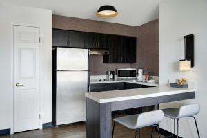 a kitchen with a refrigerator and some chairs in it at Residence Inn Merrillville in Merrillville