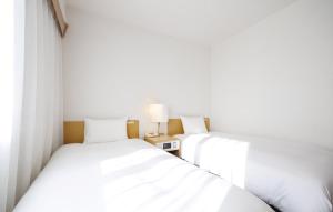 two beds sitting next to each other in a room at Court Hotel Mito in Mito