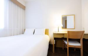 a hotel room with a bed and a desk and a mirror at Court Hotel Mito in Mito