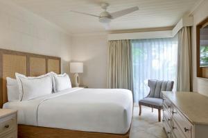 a bedroom with a large white bed and a chair at Treasure Beach Art Hotel, An Autograph Collection All-Inclusive Resort in Saint James +39 photos