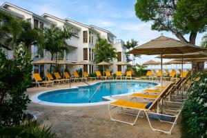 a resort pool with lounge chairs and umbrellas at Treasure Beach Art Hotel, An Autograph Collection All-Inclusive Resort in Saint James