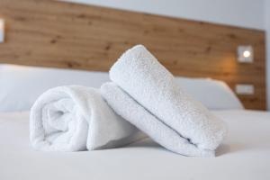 a pile of white towels on a bed at Donosti rooms in Loyola