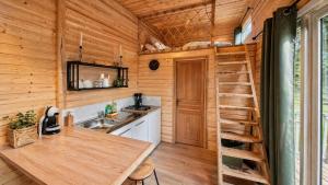a kitchen with wooden walls and a staircase in a tiny house at Cabane insolite en pleine nature - La cabane de Dim in Grumesnil