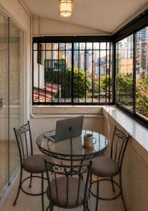 a table with chairs and a laptop on it in a balcony at Refúgio com Varanda, Wi-Fi Rápido, 450m da Praia, seu Cantinho em BC in Balneário Camboriú