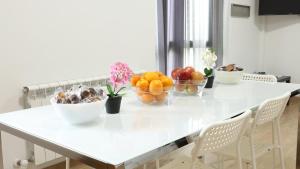 a white table with bowls of fruit on it at Sleeping portomarin 1 in Portomarin