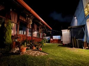 a house with a grass yard next to a building at Hotel-cafetería TERRAVOLCAN in San Pedro Sacatepéquez