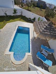 an overhead view of a swimming pool with two blue chairs at villa amani in Al Maqārisah +4 photos