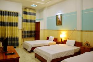 a hotel room with two beds and a television at Vien Duong Hotel in Quy Nhon