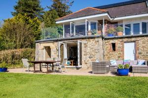 a stone house with a table and chairs in a yard at Seascape at coed y berclas, luxury accommodation with stunning sea view in Llandegfan