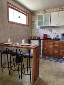 a kitchen with a wooden table and some bar stools at Bangalo Bela Vista in Caparaó Velho