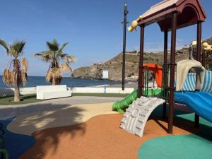 a playground with a slide in front of the water at Ikigai Home in La Rábita