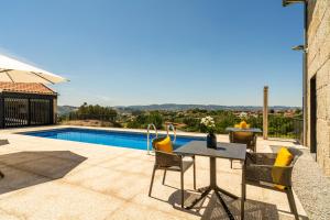 a patio with a table and chairs next to a pool at Outeyro Retreat Country House in Marco de Canaveses