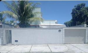 a white garage with a gate and a palm tree at Suítes Nina e Malu in Santa Cruz Cabrália