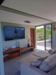 a living room with a couch and a flat screen tv at Casa Luar da Sereia - Itacaré in Itacaré