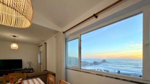 a room with a large window with a view of the ocean at Apartamento Sto Estevão in Zambujeira do Mar