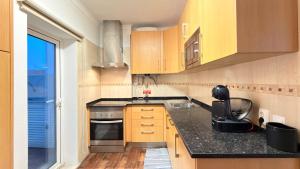 a kitchen with wooden cabinets and a black counter top at Apartamento Sto Estevão in Zambujeira do Mar